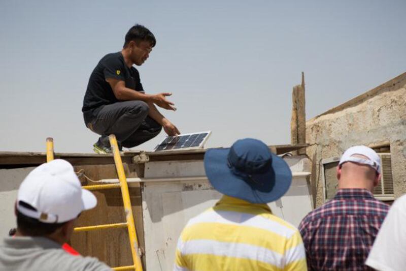 Monyati Initiative volunteers help to install solar panels at a farm near Mirfa, Abu Dhabi emirate. The solar panels connect to a fan, two lamps and a mobile phone charger in each of the 55 farms the project will eventually cover. Courtesy Amelia Johnson