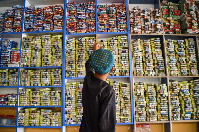 A child chooses a thread spool from a display at a tailor's shop in Kandahar, southern Afghanistan, ahead of Eid Al Adha. AFP