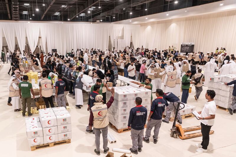 Rows of volunteers and charity workers pack and stack the boxes of aid for Gazans, at Al Rimal Hall in Dubai.