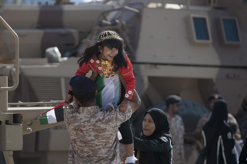 Sheikha Rafat Bawazir gets a lift up onto an army vehicle while she and her family attend a military display along the Corniche Road in Abu Dhabi. Silvia Razgova / The National