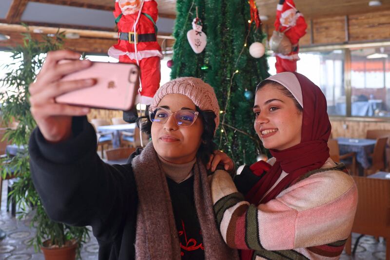 Women take a selfie with a Christmas tree at a coffee shop in Gaza city, in the Gaza Strip. AFP