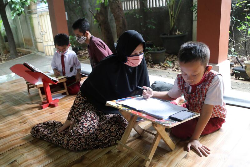 An Indonesian pupil uses a smartphone while being home schooled by his mother, in Depok, West Java, Indonesia. EPA