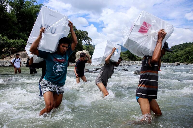 Indonesian election workers carry ballot boxes as they cross a river to deliver them to remote villages in Maros, South Sulawesi, Indonesia.