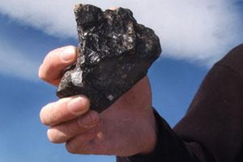 A scientist holds a stony meteorite that fell on a Colorado farm in 2004 while volunteers search for more.