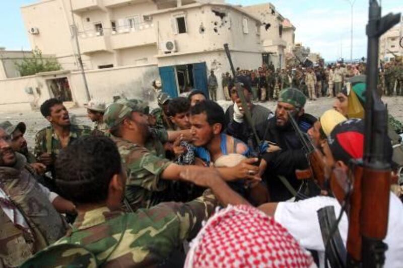 Troops of Llibya's new regime capture a wounded loyalist fighter  during battles on October 19, 2011 in Sirte's neighbourhood Number 2, one of the last two bastions of ousted leader Moamer Kadhafi's gunmen.  

AFP PHOTO/AHMAD AL-RUBAYE

 *** Local Caption ***  090363-01-08.jpg