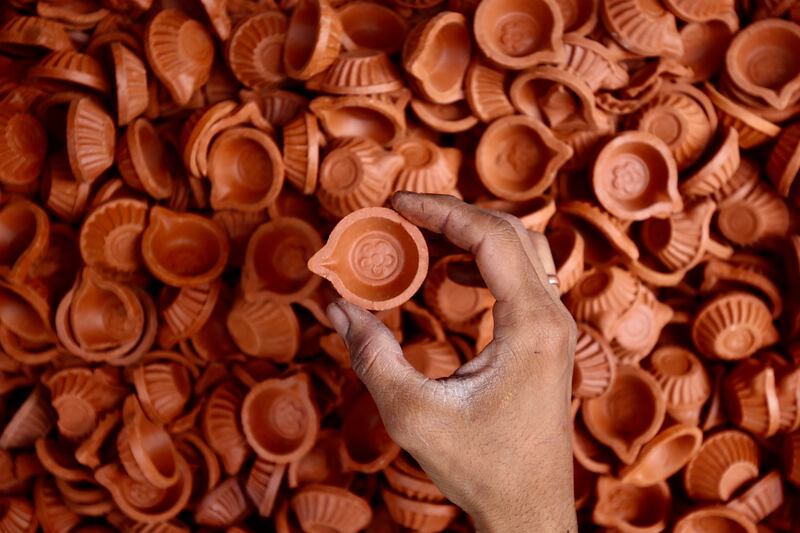 An Indian shopkeeper arranges earthen oil lamps for sale ahead of Diwali, the Festival of Lights, in Bangalore, India. EPA