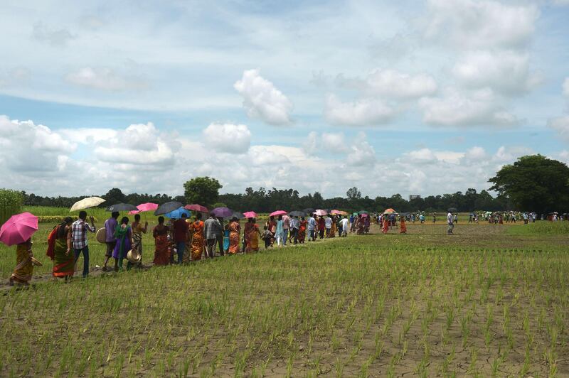 Indian villagers cross a field to attend a snake fair at Purba Bishnupur village, around 85 kms north of Kolkata on August 17, 2013.  Hundreds of people queued in a remote village in eastern India over the weekend to receive blessings from metres-long and potentially deadly snakes, thought to bring them good luck.  AFP PHOTO/Dibyangshu SARKAR
 *** Local Caption ***  761197-01-08.jpg