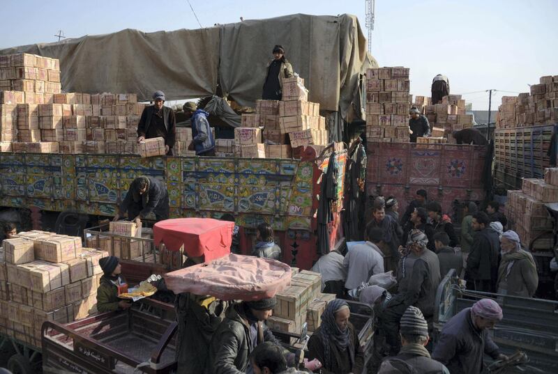 Afghan labourers unload crates of fruit from a truck at a fruit market in Mazar-i-Sharif on January 26, 2018. / AFP PHOTO / FARSHAD USYAN