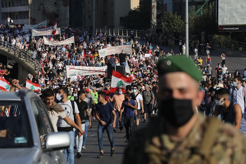 Lebanese army vehicles escort crowds walking over a bridge linking the city on the first anniversary of anti-government protests. Getty Images