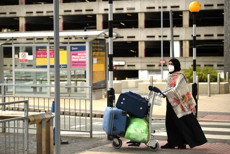 A passenger pushes her luggage after arriving at Manchester Airport. AFP