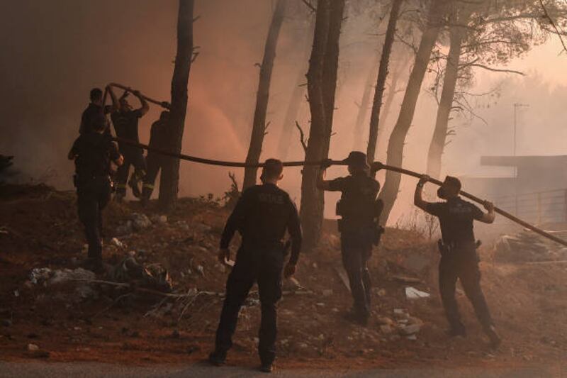 Police officers help firefighters extinguish a fire in Thrakomakedones, near Mount Parnitha, north of Athens. Louisa Gouliamaki / AFP