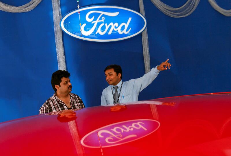 FILE PHOTO: An employee speaks to a potential customers next to a Ford car inside the company's showroom in Mumbai, March 3, 2012. REUTERS/Danish Siddiqui/File Photo