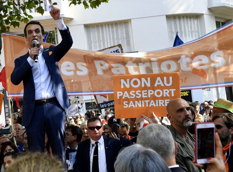 Florian Philippot of the nationalist The Patriots party speaks at a demonstration in Paris. A protester holds a placard with the message 'No to health passport'.