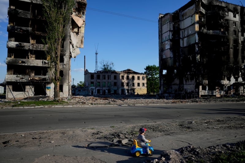 A child plays against a backdrop of buildings ruined by shelling in Borodyanka, Ukraine. AP