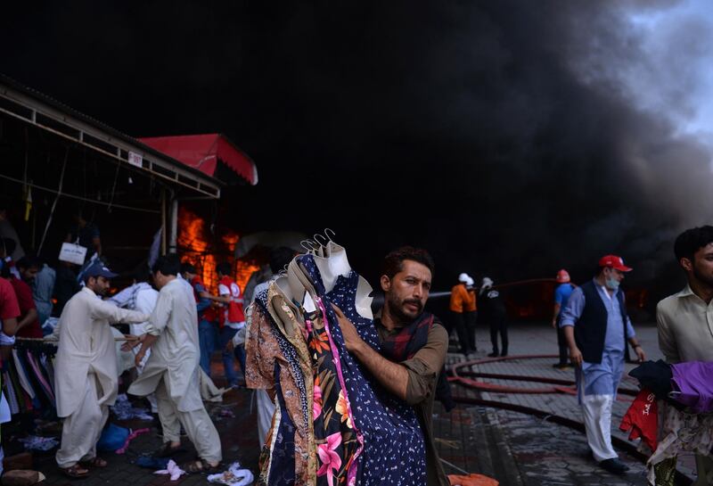 Pakistani traders move stock out of a shop.