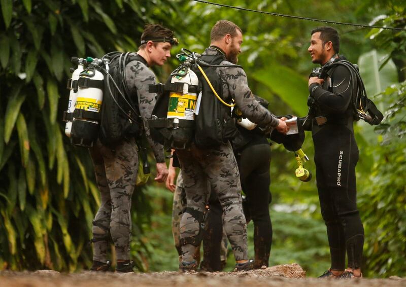 Australian Federal Police and Defense Force personnel talk to a Thai rescuer, right, before diving after the 12 boys and their soccer coach were found alive, in Mae Sai, Chiang Rai province, in northern Thailand, Tuesday, July 3, 2018. The 12 boys and soccer coach found after 10 days are mostly in stable medical condition and have received high-protein liquid food, officials said Tuesday, though it is not known when they will be able to go home. (AP Photo/Sakchai Lalit)