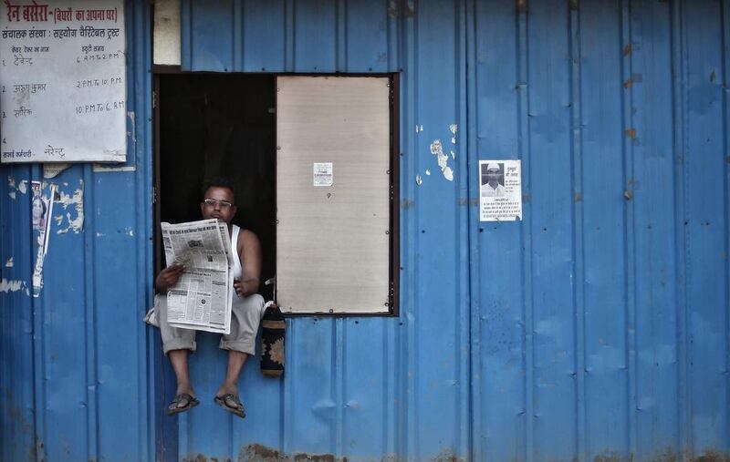 A man reads a newspaper as he sits on the window of a temporary shelter for homeless people in New Delhi. Adnan Abidi / Reuters