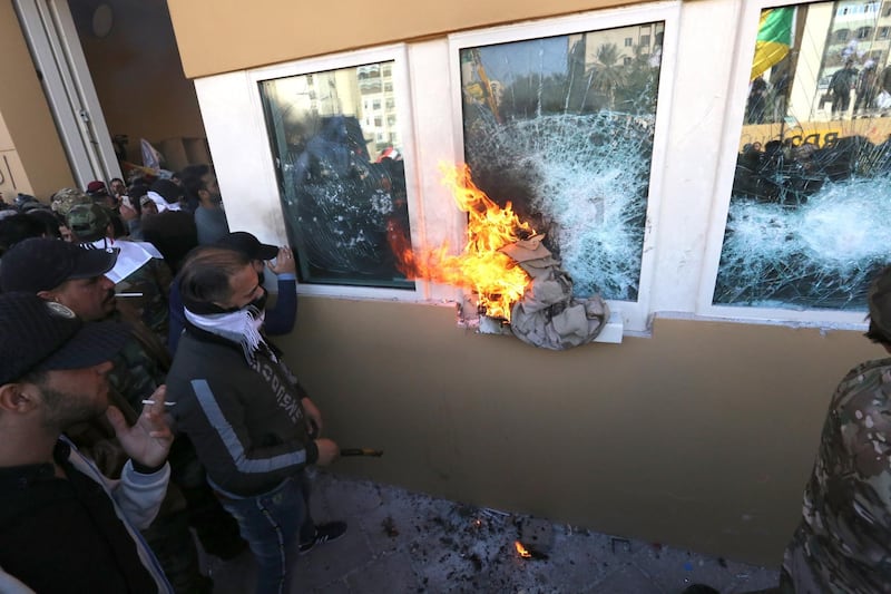 epa08096633 Members of Iraqi Shiite 'Popular Mobilization Forces' armed group and their supporters attack the entrance of the US Embassy in Baghdad, Iraq, 31 December 2019. According to media reports, the US ambassador and other members of the staff were evacuated as dozens of people broke into the embassy's compound after setting fire to the reception area. The attack at the embassy follows a deadly US airstrike that killed 25 fighters of the Iran-backed militia on 29 December.  EPA/AHMED JALIL
