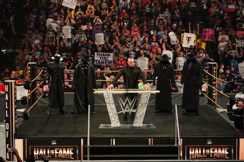 The Undertaker stands in the ring with different variations of his wrestling outfit.