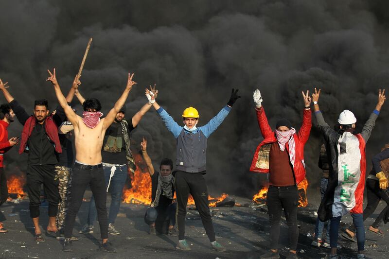 Iraqi protesters flash victory signs amid clashes with riot police following a demonstration at Baghdad's Tayaran Square, east of Tahrir Square. AFP