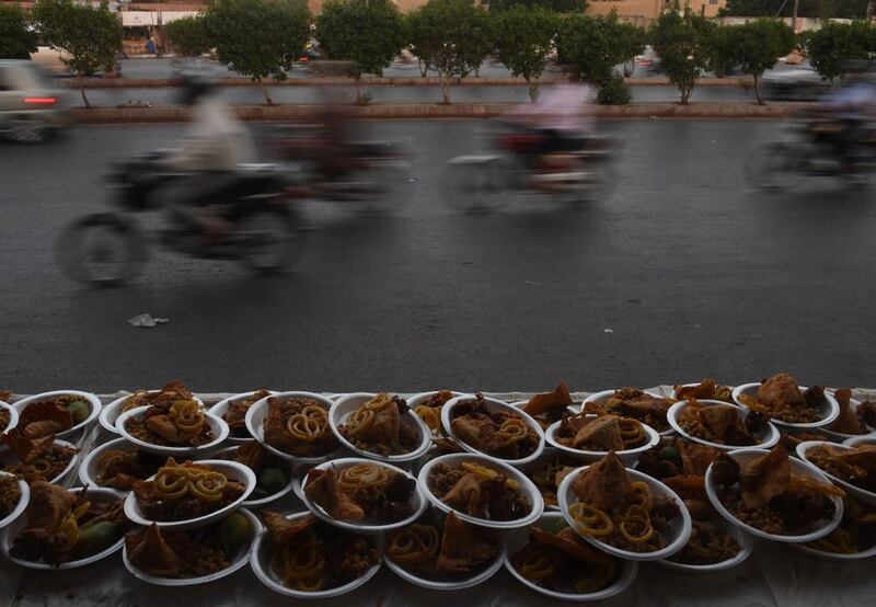 Pakistan motorcycle riders in Karachi drive past plates of food for iftar. Asif Hassan / AFP Photo