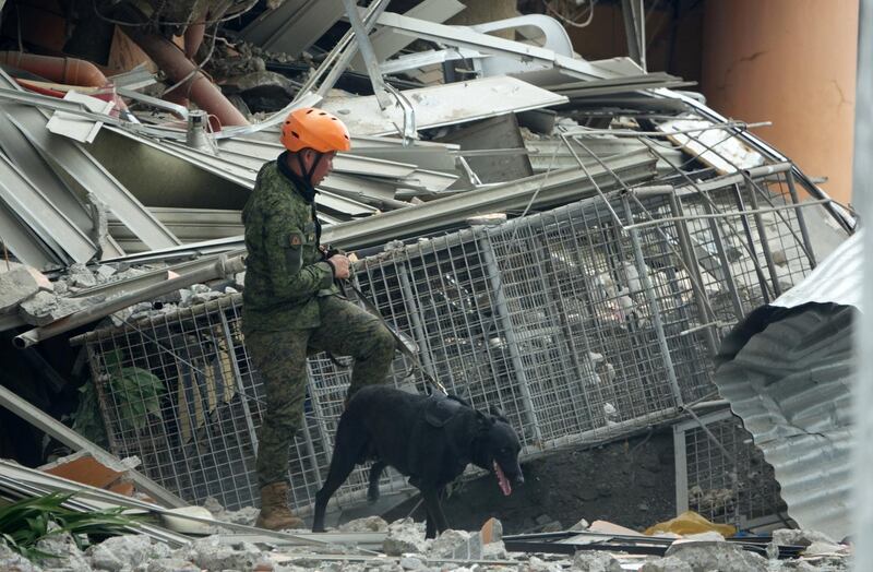 epa07961770 A Filipino K-9 officer inspects a damaged hotel in the aftermath of a 6.5 magnitude earthquake, in Kidapawan city, Cotabato province, Philippines, 31 October 2019. According to the United States Geological Survey (USGS), a 6.5 magnitude earthquake occurred at a depth of 10km near Bulatukan, Cotabato province, on 31 October. It is the third strong earthquake the area has experienced this month.  EPA/CERILO EBRANO