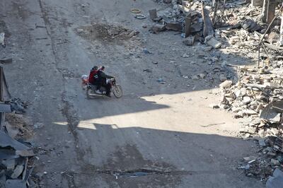 TOPSHOT - Syrian men ride a motorcycle through a damaged neighbourhood in Maaret Al-Numan city in Syria's northwestern Idlib province on January 13, 2020.  / AFP / Abdulaziz KETAZ
