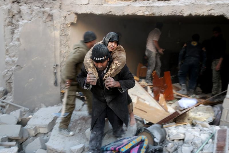 A Syrian rescuer carries a woman who was found alive in the rubble of a building in Aleppo's rebel-held district of Al Hamra on November 20, 2016. Thaer Mohammed / AFP
