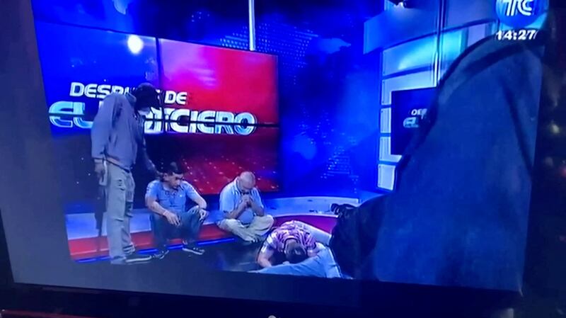 Workers sit on the floor as hooded and armed people take over Ecuador's TV station TC during a live broadcast on January 9. Reuters