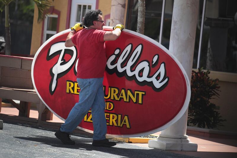 A worker removes a sign from the front of a restaurant  in Indialantic, Florida. AFP