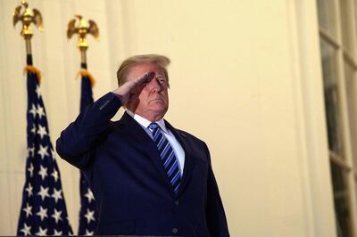 US President Donald Trump salutes from the Truman Balcony upon his return to the White House from Walter Reed Medical Center, where he underwent treatment for Covid-19, in Washington, DC, on October 5, 2020.  / AFP / NICHOLAS KAMM
