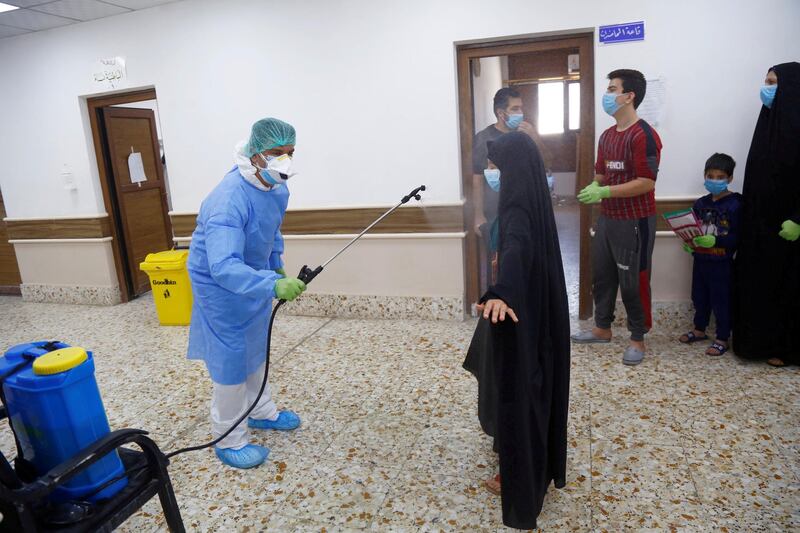 A nurse wearing protective suit and face mask sprays a girl who was infected with the coronavirus disease (COVID-19) and has recovered, with sterile water, in quarantine ward, at a hospital in the holy city of Najaf, Iraq. REUTERS