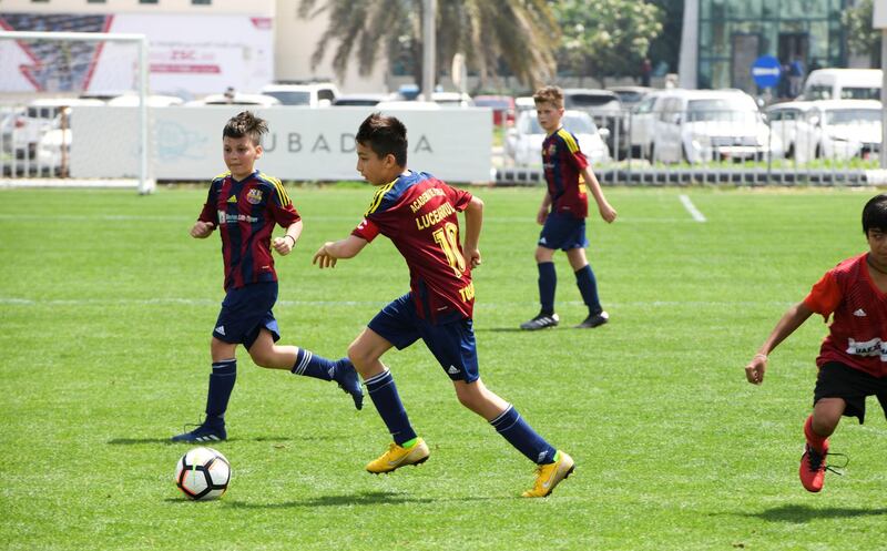 Abu Dhabi, United Arab Emirates - Etihad Sports Academy (plain red) vs Luceafarul from Romania (red/blue strips) under 12 age group on Abu Dhabi World Cup Day 1 at Zayed Sports City. Khushnum Bhandari for The National
