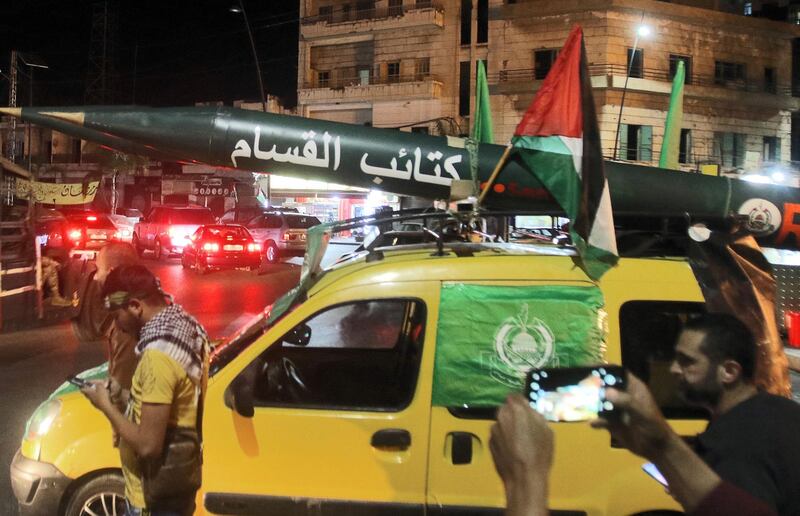 Men parade with a makeshift rocket written in Arabic, "Qassam Brigades" (Hamas armed wing) during a demonstration called by the Palestinian Islamist group Hamas in the southern Lebanese city of Saida late on May 11, 2021. / AFP / Mahmoud ZAYYAT
