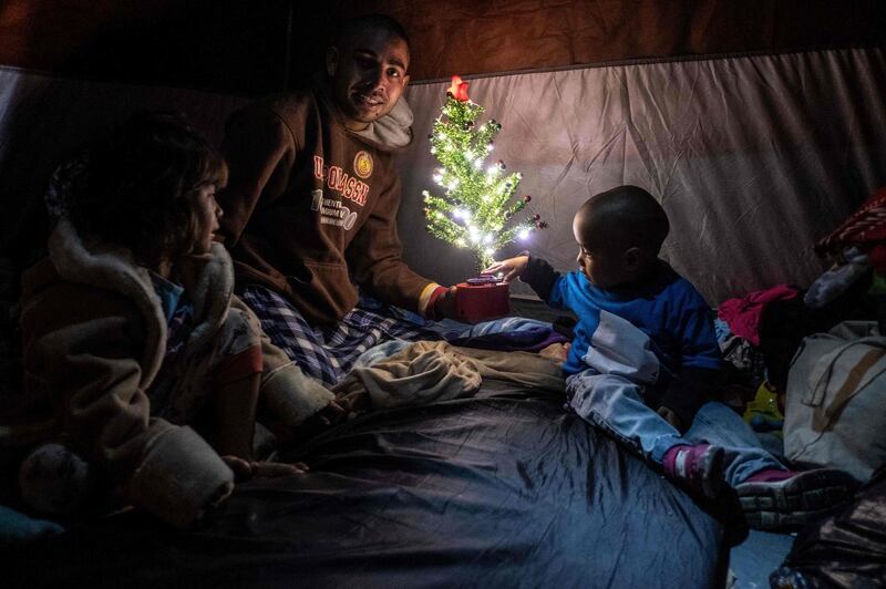 Members of Honduran migrant family Aguilar Duarte, who traveled with the Central American migrants caravan to the Mexico-US border, pose for a picture with a Christmas tree inside their tent at a temporary shelter in downtown Tijuana, Baja California state, Mexico. AFP