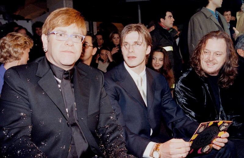 Elton John, in a black suit with sparkling detail, with David Beckham and Italian singer Zucchero Fornaciari during Versace's autumn/winter 1998-99 show in Milan on January 11, 1998. EPA