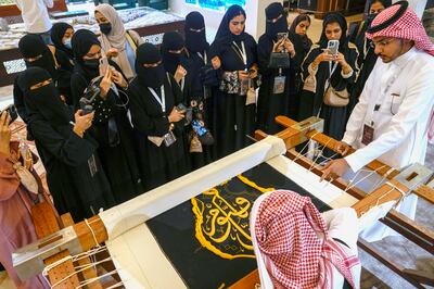 Saudi students film Ahmed Al Humani as he embroiders Islamic calligraphy on the Kiswa, which covers the Kaaba at the heart of the Grand Mosque. AP