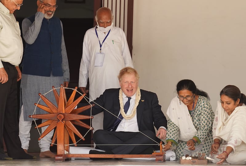 Boris Johnson is shown how to operate a spinning wheel at the Sabarmati Ashram, also known as Gandhi Ashram, in Ahmedabad. Getty Images