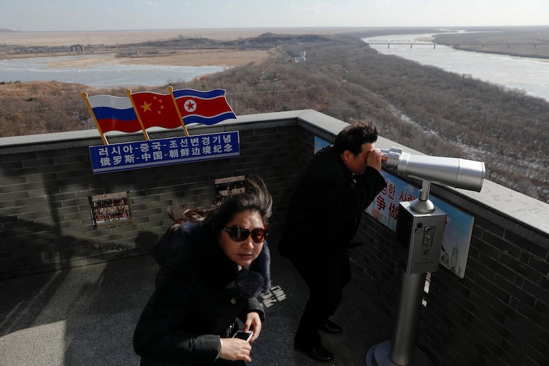 A tourist uses binoculars to look across to North Korea from a tower built on the Chinese side of the border between Russia (L), China (C) and North Korea (R) near the town of Hunchun in China, November 24, 2017. REUTERS/Damir Sagolj  SEARCH "SAGOLJ ROAD TRIP" FOR THIS STORY. SEARCH "WIDER IMAGE" FOR ALL STORIES.