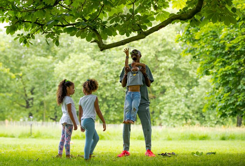 Farah lifts his son Hussein as his twin daughters Aisha and Amani look on during a family day out in St James' Park, London, in 2018. Getty Images