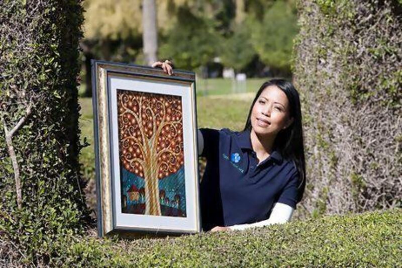 Desiree Vlekken, the founder of 4get-me-not.org, holds up a painting by the Filipino artist Jomike Tejido, titled The Memory Tree. Mike Young / The National