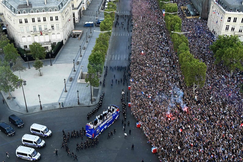 France's fans greet France's national football team players as they celebrate on the roof of a bus while they parade down the Champs-Elysee avenue in Paris.  AFP / Bertrand GUAY