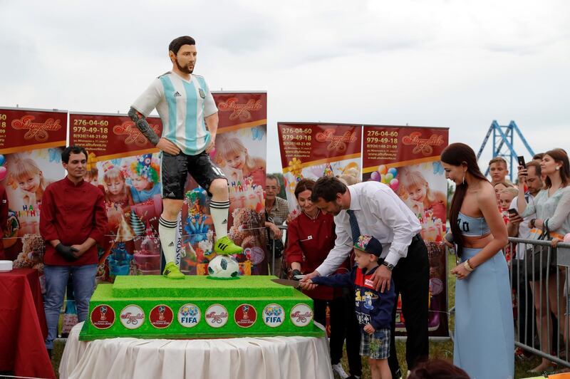 The mayor of Bronnitsy helps a boy cut a cake to mark Lionel Messi's birthday. AP