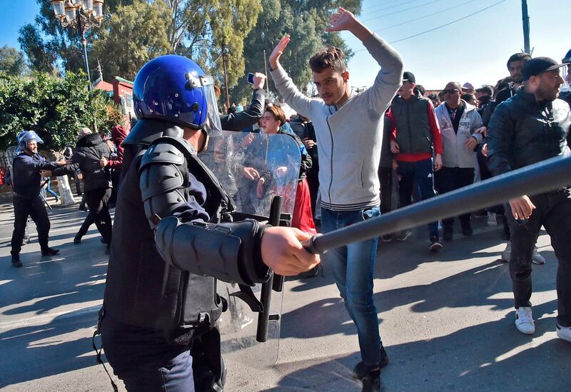 Algerian demonstrator stands in front of a police officer during a demonstration against Algeria's president's candidacy for a fifth term. AFP