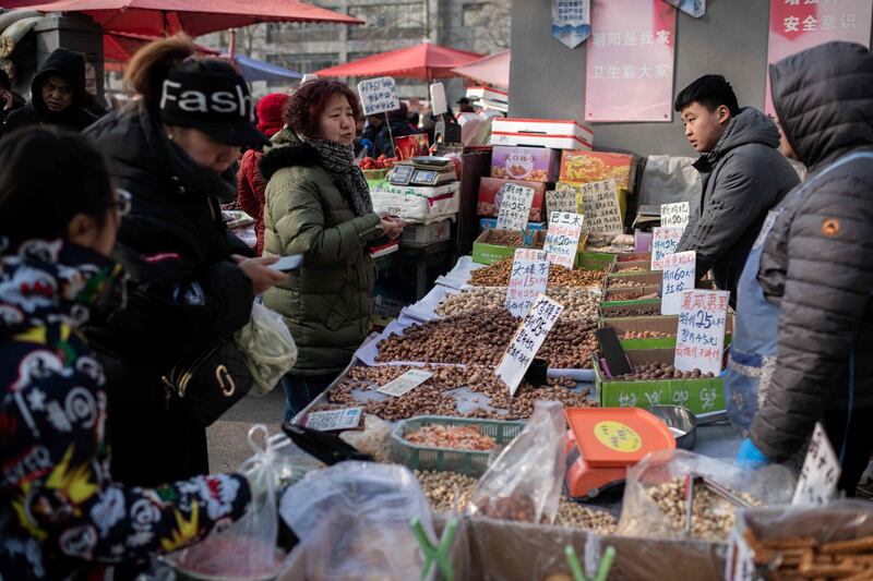 People buy nuts at a market in Beijing on January 17, 2020. China's economy weakened to its slowest pace in three decades in 2019 as weaker domestic demand and trade tensions with the United States took their toll, official data showed on January 17. / AFP / Nicolas ASFOURI
