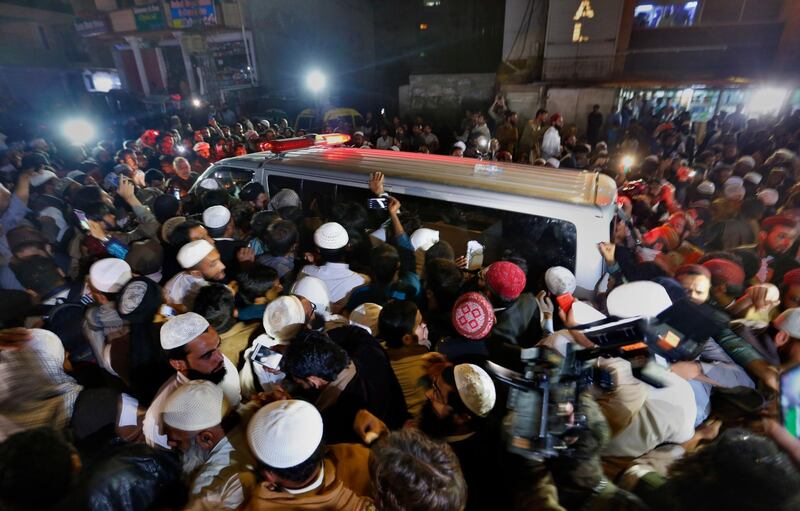 People gather around an ambulance carrying the body of Pakistani cleric Maulana Samiul Haq, leaving a hospital in Rawalpindi, Pakistan, Friday, Nov. 2, 2018. Haq, who was often called "father of the Taliban," was killed in a knife attack at his home in the garrison city of Rawalpindi on Friday, his family and police said. (AP Photo/Anjum Naveed)