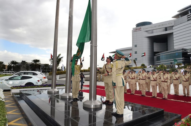 The flag with Dubai Police's new corporate identity Maj Gen Abdullah Khalifa Al Marri is raised on Thursday at Dubai Police general headquarters. Courtesy Dubai Police