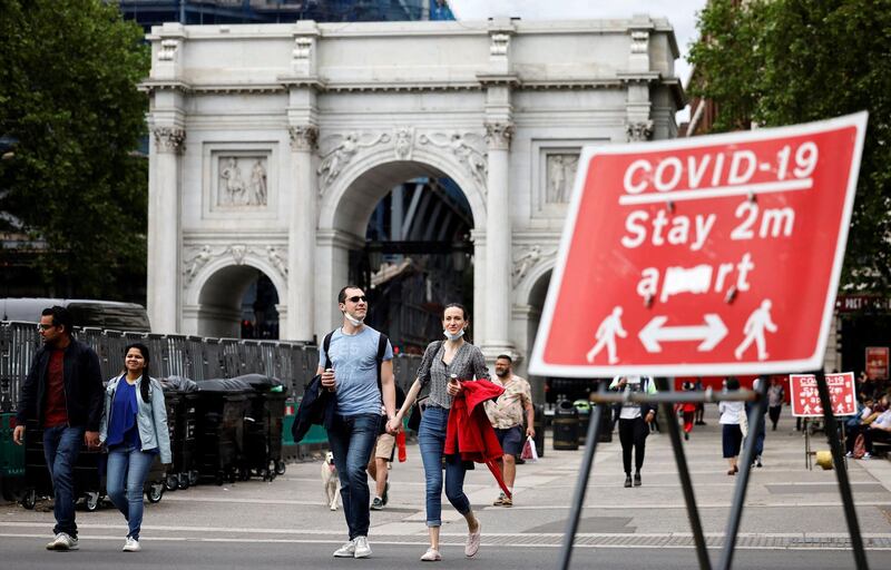 Pedestrians walk past a sign asking people to social distance, near Marble Arch in central London. AFP