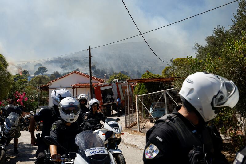 Police officers attend to a wildfire in the village of Markati, near Athens, Greece.