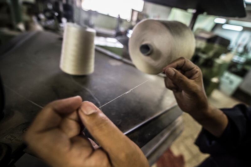 A worker threads a sewing machine. AFP